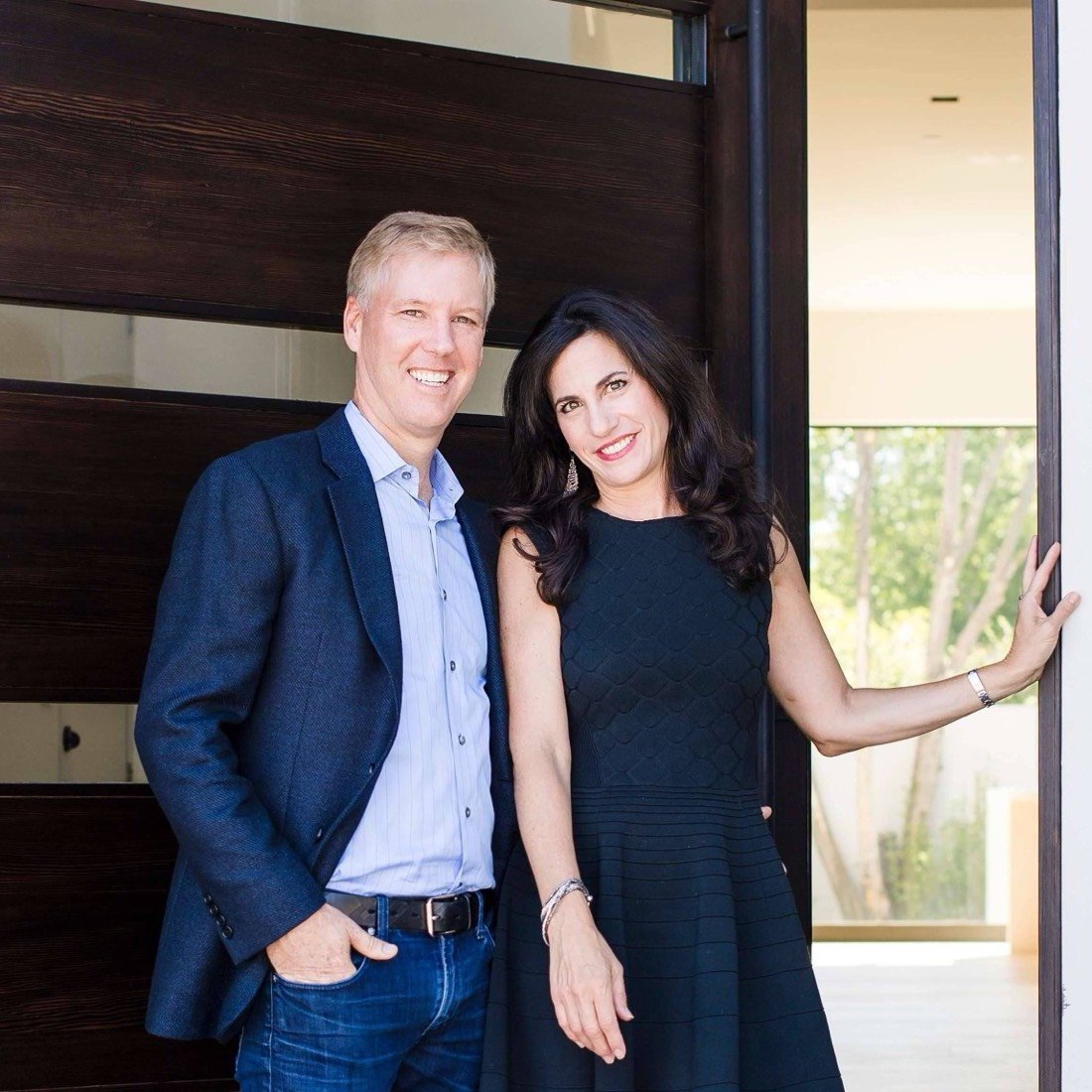 Eric and Janelle Boyenga standing at the dark wood front door of a modern home